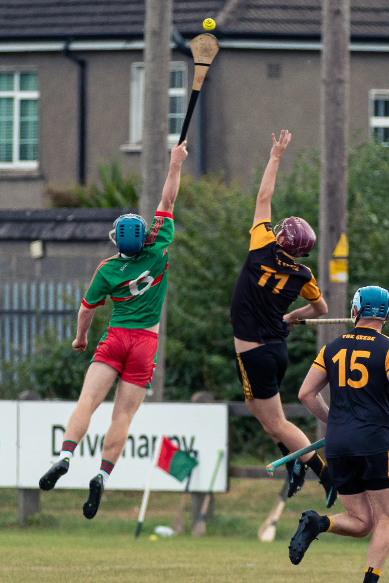 A Naomh Barróg hurler stretches overhead for a dropping sliotar as a Wild Geese player challenges at Pairc Barróg.